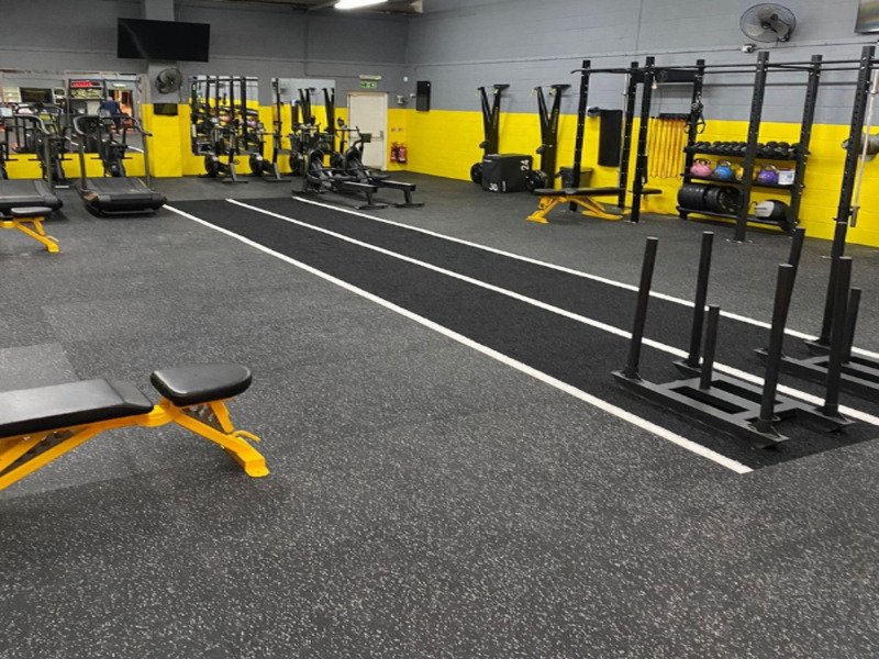 Athlètes effectuant des poussées en luge sur la pelouse officielle de Hyrox lors d'une compétition